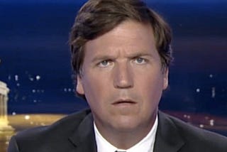 A photograph of Tucker Carlson facing the viewer and looking confused.