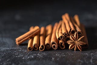 Stack of cinnamon with a star anise on a black surface.