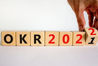 A series of wooden blocks in a row, which spell out “OKR 2022”, changing from 2021.