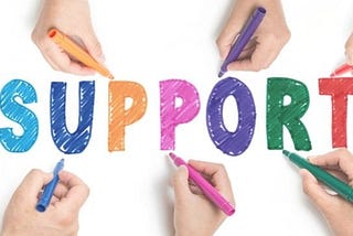 A photo of several people drawing out the word “support” on paper