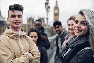 A group of teenagers smile at the camera outside Westminster.