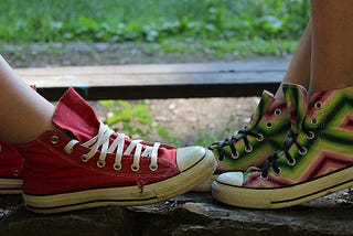 A pair of feet in a pair of canvas shoes facing each other as though in a conversation