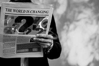 Un uomo legge un quotidiano su cui si legge “The world is changing”