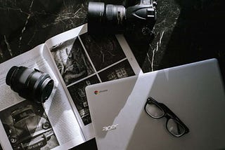 Camera with laptop over a photo book in black and white