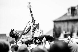 Profile of a guitar player crowd surfing on his back while playing. Photo courtesy of Thibault Trillet at Pexels