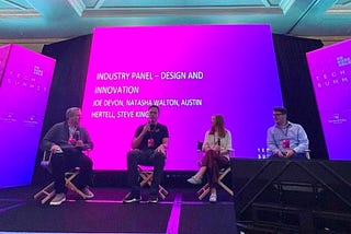 The four panel participants on stage in front of a pink and purple screen that reads “Industry Panel — Design and Innovation”