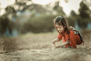 Girl in red playing with sand.