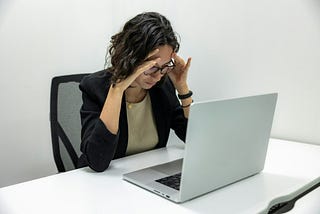 a woman sitting in front of a laptop computer suffering from toxic productivity