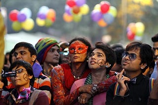 People from the LGBTQ community of India look up as balloons float in the background