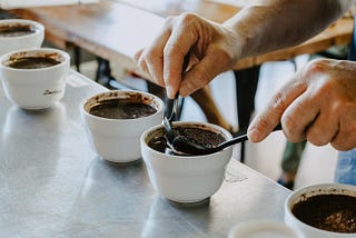 a cup of coffee with the grounds being scooped off the top