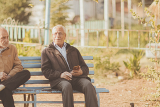 An image of two older gentlemen sitting on a bench together