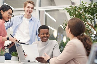 How to Land your First Internship and 15 Tips for a Successful Internship | Group of 4 interns around a table smiling 