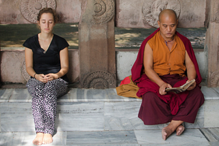 In this image it is the lay person on the left who appears to be meditating, and not the monk on the right, who is reading.(Ghosh/Tapasphotography/flickr).