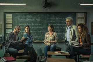 Promotional image for “Segunda Chamada”. Five people (2 men and 3 women, they are all teachers) in a classroom talking to each other.