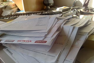 A pile of paperwork on a cluttered desk.