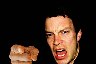 An angry man points and shouts