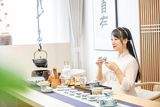 A woman sits in front of a table of tea-related items. Tea ceremonies are popular throughout Asia. The partaking of tea is considered a practice of equanimity. | Source: kimmi jun, Pexels