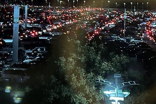 Row of cars in a congested parking lot. The rear, red brake lights are all lit. Nobody is moving.