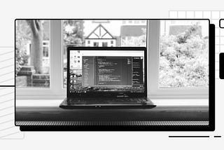 A computer with an open IDE in front of a window.