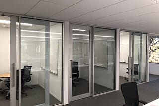 a row of offices with sliding glass doors, with whiteboards, in an Apple office in Cupertino. Having offices with doors is probably why Apple is a trillion dollar company, I’m sure of it.