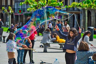 Children play in the middle of a city, not in a fenced-off playground. With bubbles, toys — and no cars.