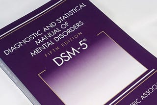 This is a photo of the front cover of the American Psychiatric Association’s Dianostic and Statistical Manual of Mental Disorders, Fifth Edition.
