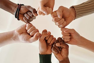 Six fits of diverse races joined together around a circle in solidarity