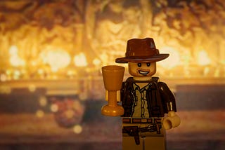 A Lego version of Indiana Jones is posed holding a cup representing the Holy Grail.