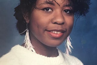 A photo of the author at age 15 wearing neon white feather earrings and a white vintage sweater vest. She felt very punk rock at this age!