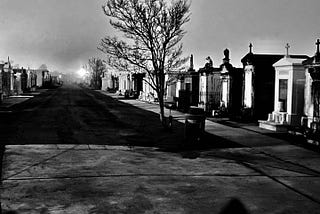 A spooky black and white photo of Saint Louis Cemetary #3 while hell rages overhead within the clouds