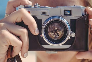 woman looking through the viewfinder of a camera