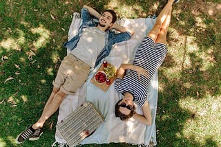 man and woman relaxing in the shade and having a picnic of fruit
