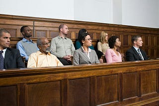Ordinary people sitting in a jury box in a wood-panelled courtroom