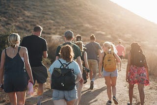 people walking on dirt road near mountain during daytime