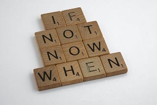 Scrabble tile letters form the phrase “If not now, when.”