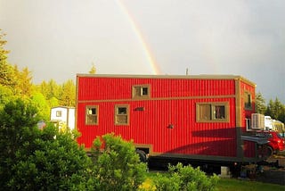 red tiny house with a rainbow ending in the center
