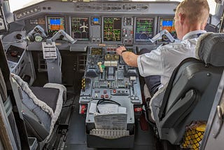 View of an airplane cockpit with a pilot checking the instrument panel