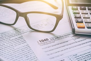 Tax forms laid out on a desk next to a pen and calculator