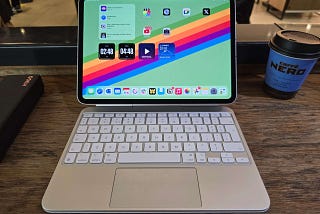 An 11-inch M4 iPad Pro on a wooden desk, attached to a white magic keyboard.