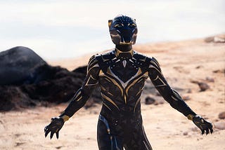 The new Black Panther in a new Black Panther costume stands on a beach in Black Panther: Wakanda Forever.