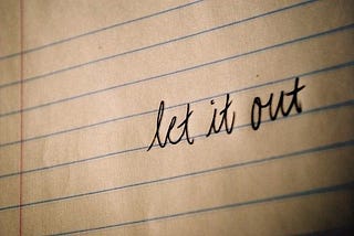 Handwritten words on lined paper saying Let it Out