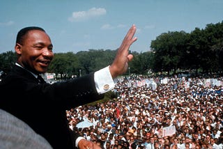 Dr. Martin Luther King Jr. smiling and waving to the crowd gathered at the March on Washington