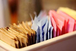 Different colorful packets of artificial sweeteners and sugars