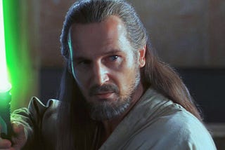 Liam Neeson in “The Phantom Menace” holding a lightsaber