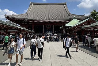 People walking around in front of a temple in Tokyo, Japan
