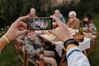 taking photo of family dinner on smartphone ready to share memories online.