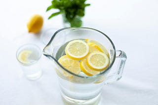 A pitcher of water with lemon slices is sitting on a white countertop.