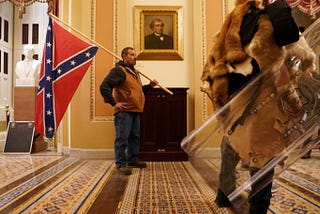 An insurrectionist carries a Confederate flag through the U.S. Capitol, January 6th 2021.