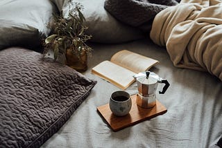 A cosy scene with blankets and pillows, coffee and books