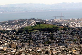 photo of Bernal Heights, San Francisco, with San Francisco Bay and the Easy Bay in the background, and a cloud shadow.